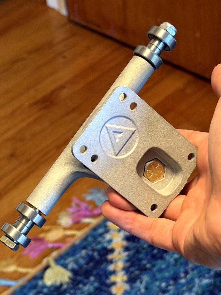 Baseplate of a metal 3D-printed Pantheon surf skate truck prototype with the Pantheon logo